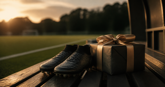 Football boots and a wrapped gift on a pitch-side bench for a Father's Day football gift guide