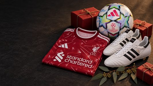 A Liverpool 26-27 home jersey, adidas Copa Mundial boots and the UEFA Champions League 26-27 ball with red gift boxes and eucalyptus leaves.